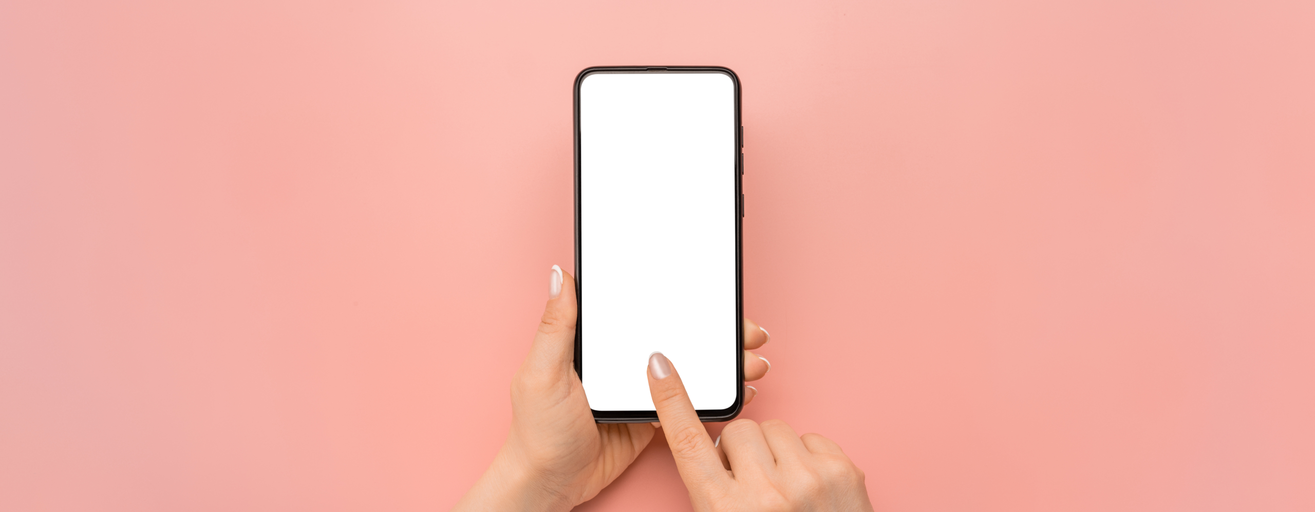 Hand holding cellphone device and touching screen on pink background. Isolated hands and smartphone on pink background. Female hand holding modern black cell phone in vertical position